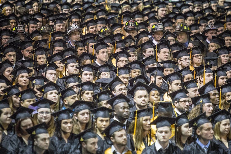A sea of faces in graduation caps and gowns