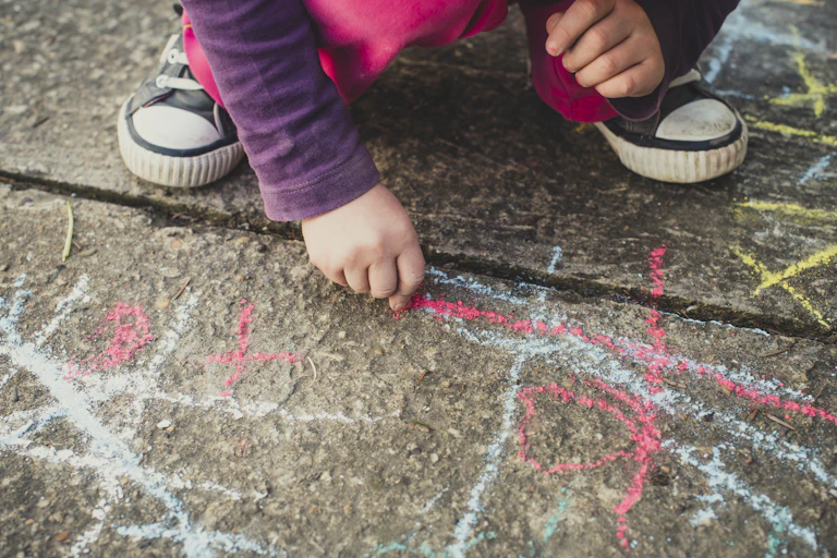 Un enfant dessine sur le sol avec une craie.