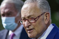 Schumer, wearing glasses, speaks at a news conference.