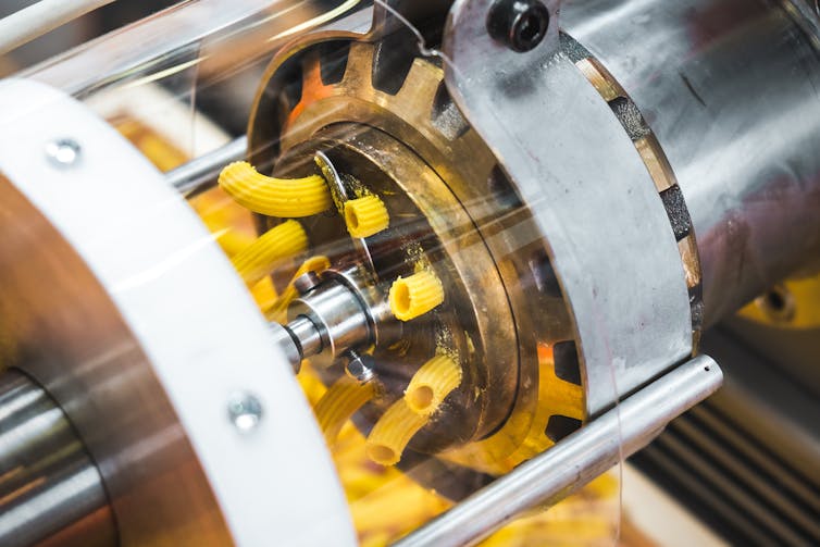 A bronze die machine extrudes pasta into a shape