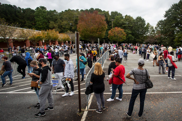People wait in long lines in a parking lot