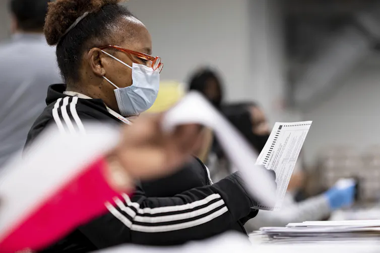 A woman in a mask handles papers