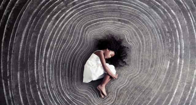 Young girl sleeps surrounded by concentric chalk outlines of her body.