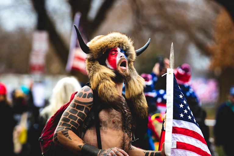 Jake Angeli wearing a fur hat and horns during the January 6th riots on Capitol Hill.