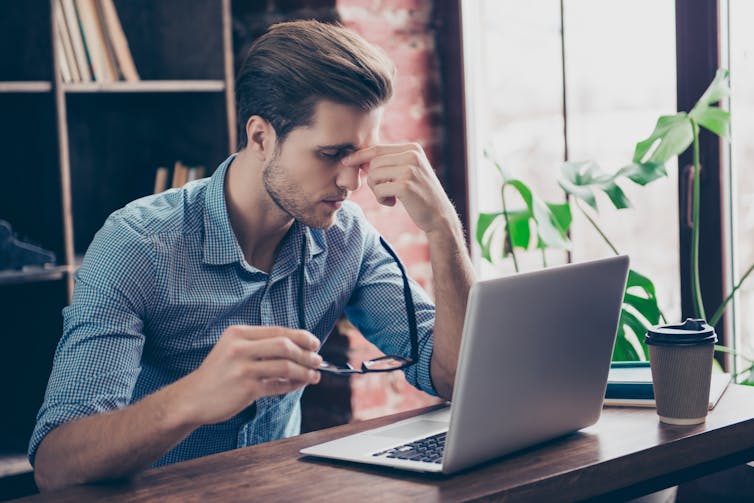 A young man using a laptop appears stressed.