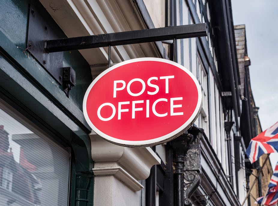 A Post Office sign hanging on a British high street