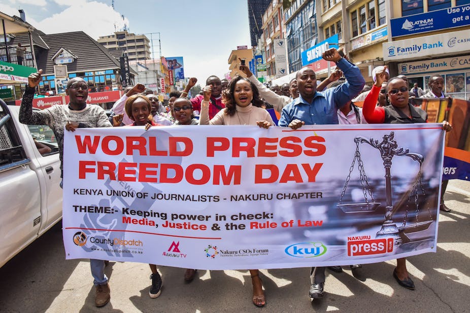 A group of men and women holding a banner while marching on the street.