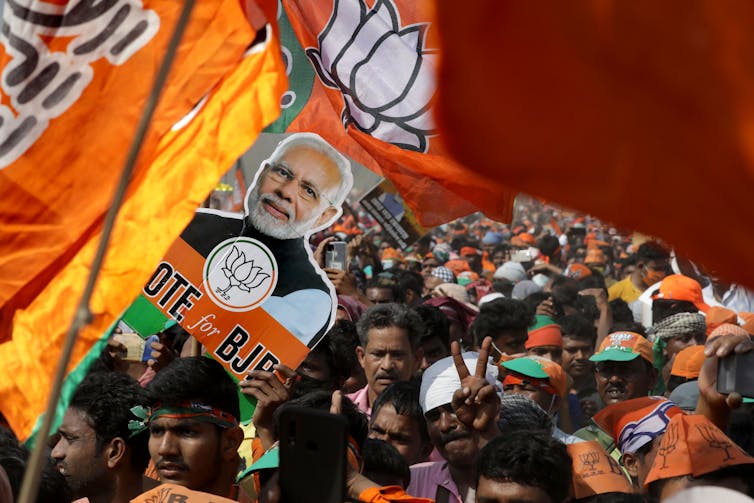 Mass rally of BJP supporters with flags and banners featuring Prime Minister Narendra Modi.