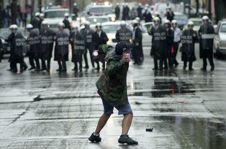 A protester throws debris at Cincinnati police officers in riot gear in 2001.