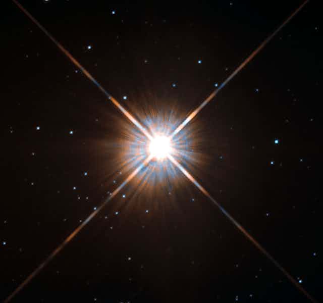 Proxima Centauri shining brightly against the backdrop of black space with small stars.