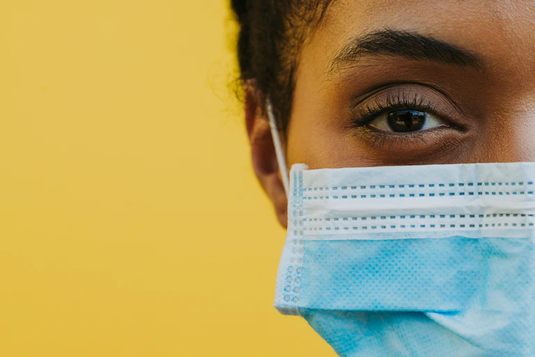 A woman weaking a face mask against a yellow background