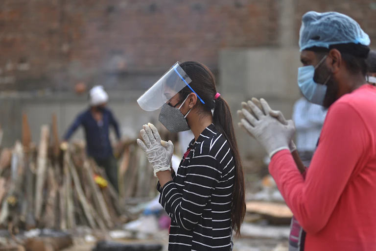 Relatives perform the last rites for COVID-19 victims during their funeral at a cremation ground in New Delhi