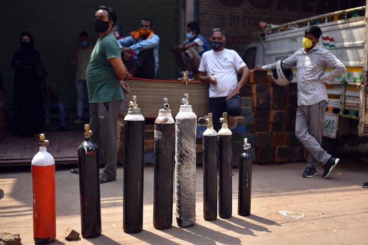 Indian people wait to fill their oxygen cylinders at an oxygen vendor shop in New Delhi.