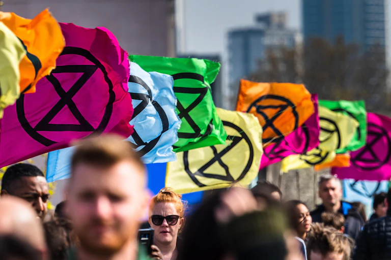 People walking beneath flags with Extinction Rebellion logo