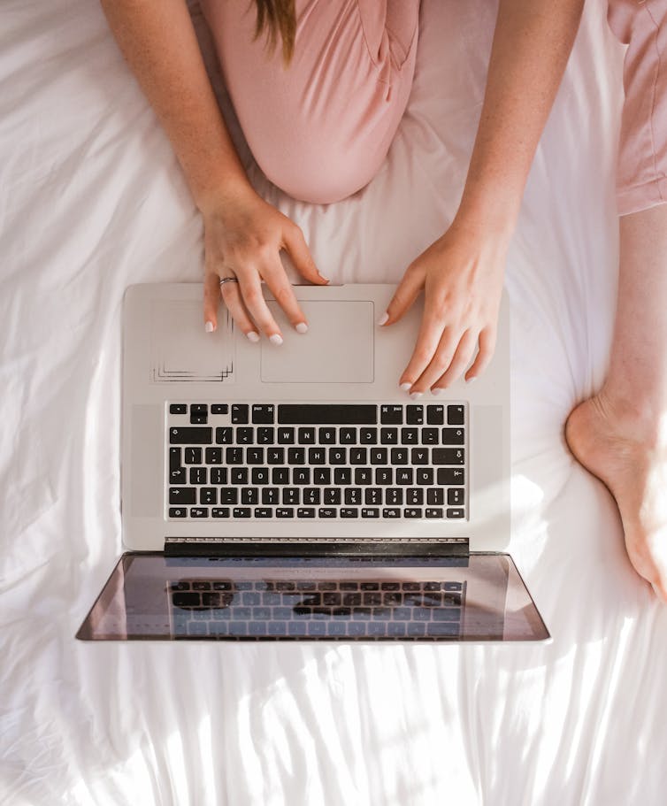 Woman working on a laptop on her bed