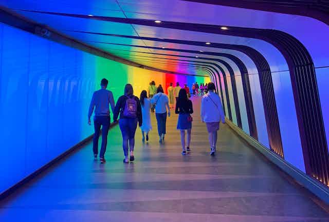 People walking down a rainbow coloured tunnel