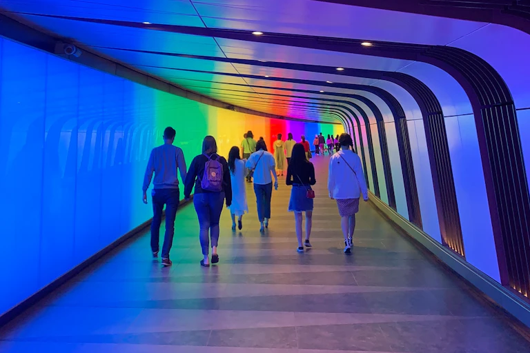 People walking down a rainbow coloured tunnel