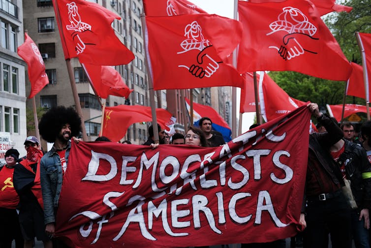 Jovem multidão de jovens segurando faixas vermelhas de 'DSA' em uma rua de Nova York