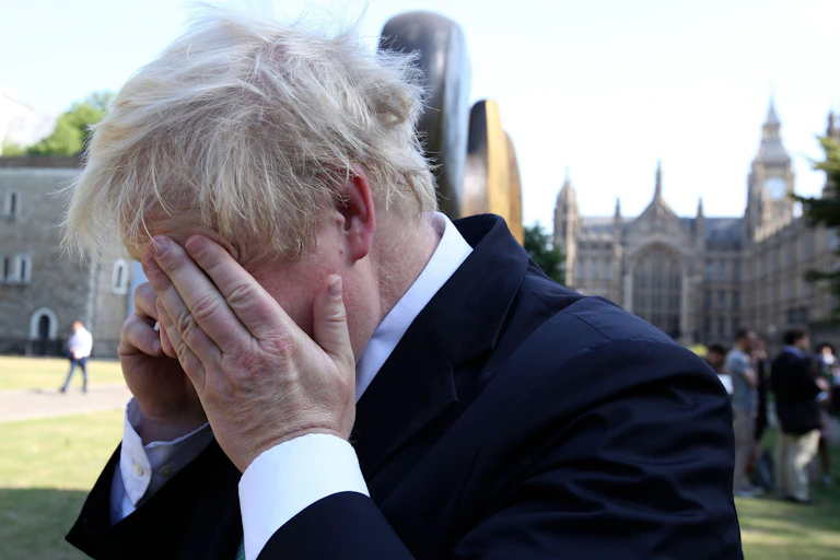 Boris Johnson rubs his eye while on the phone