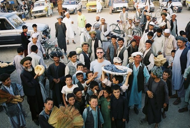 A crowd of Afghans smile around a guest