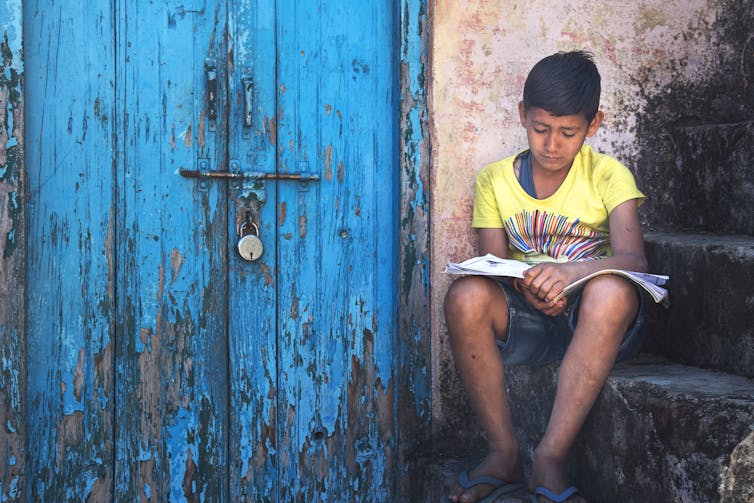 A boy reads a book on a set of steps.