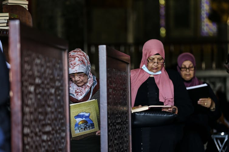 Three women recite the Quran at Al-Aqsa Mosque in Jerusalem.