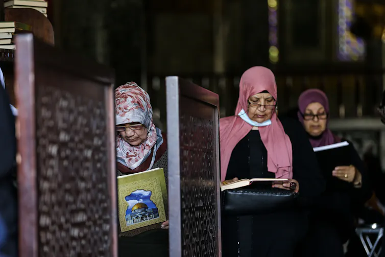 Three women recite the Quran at Al-Aqsa Mosque in Jerusalem.