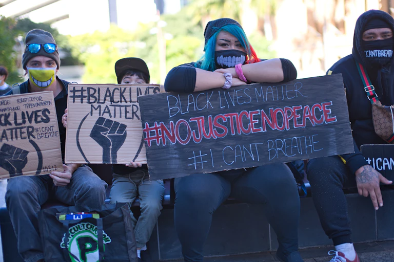 Four protesters hold signs: 'Black Lives Matter'