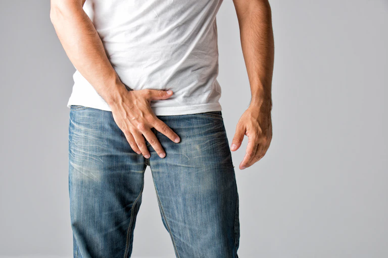 A man has his hand over his crotch.