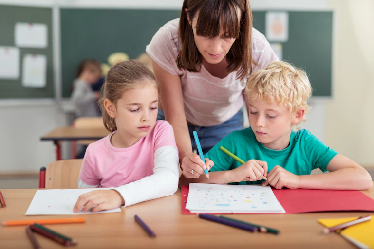 Teacher helping two students with writing.