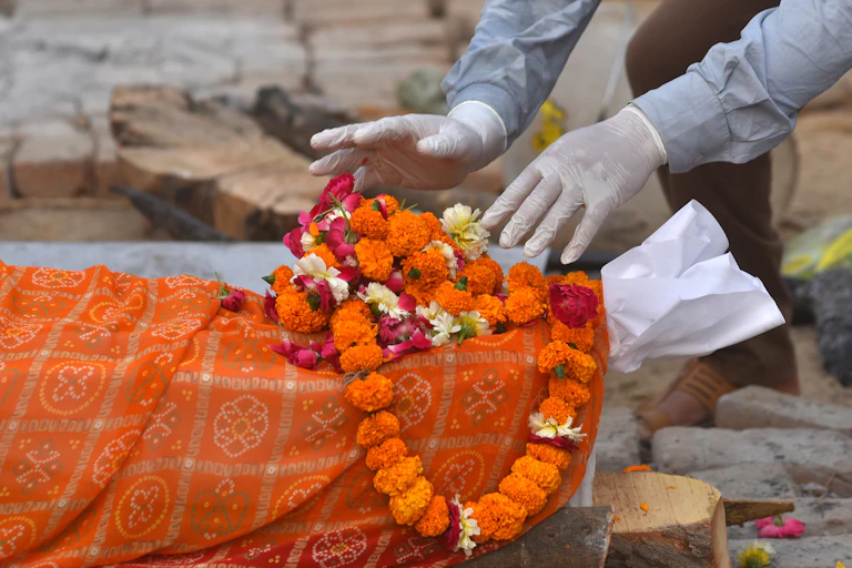 A body is prepared for the last rites at funeral pyres for COVID-19 victims at a makeshift cremation ground in New Delhi
