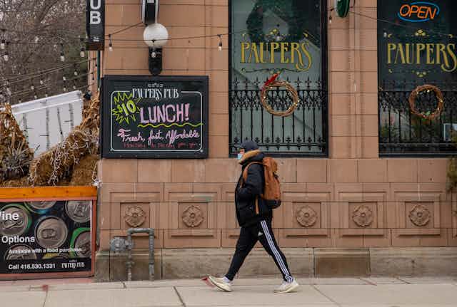 A man strolls past a sign advertising $10 lunch