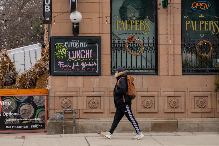 A man strolls past a sign advertising $10 lunch