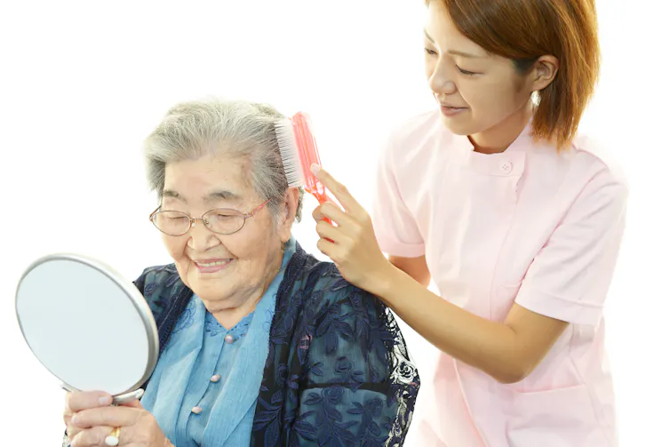 A younger woman brushing an older woman's hair.
