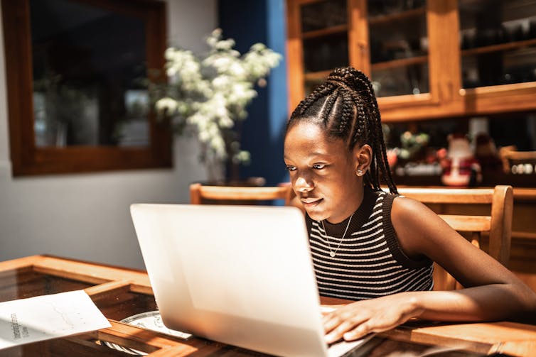 A young African American girl looks at her computer.