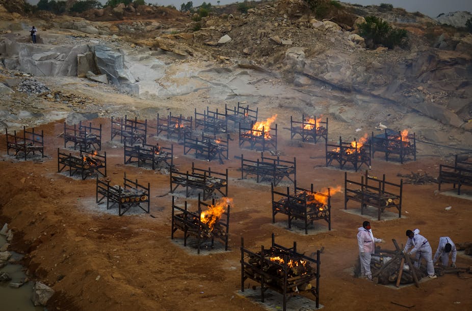 Men wearing PPE performing the last rites at a cremation ground, where mas cremations are being done, Bengaluru, India