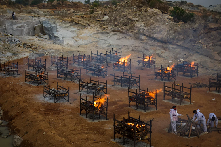 Men wearing PPE performing the last rites at a cremation ground, where mas cremations are being done, Bengaluru, India
