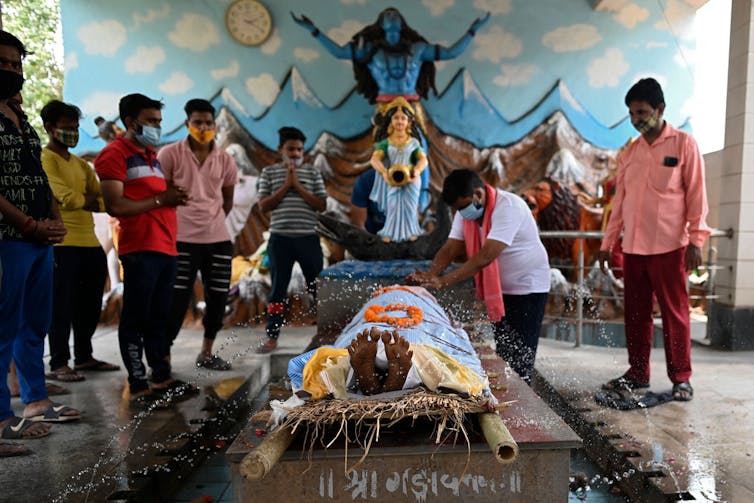 Relatives gather around the body of a man who died of COVID-19 in India, to perform religious rituals.