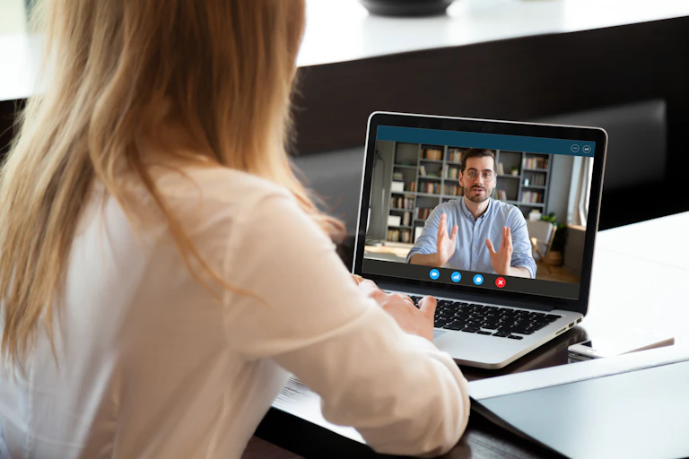 Une jeune femme suit un cours en ligne devant son ordinateur