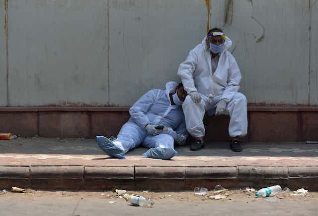 Indian health care workers take a rest outside the hospital mortuary in New Delhi, India, 29 April 2021