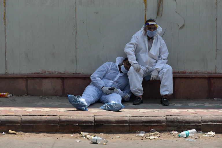 Indian health care workers take a rest outside the hospital mortuary in New Delhi, India, 29 April 2021