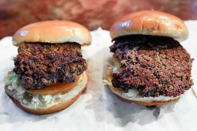 A conventional beef burger encased in a bun sits next to an Impossible burger. 