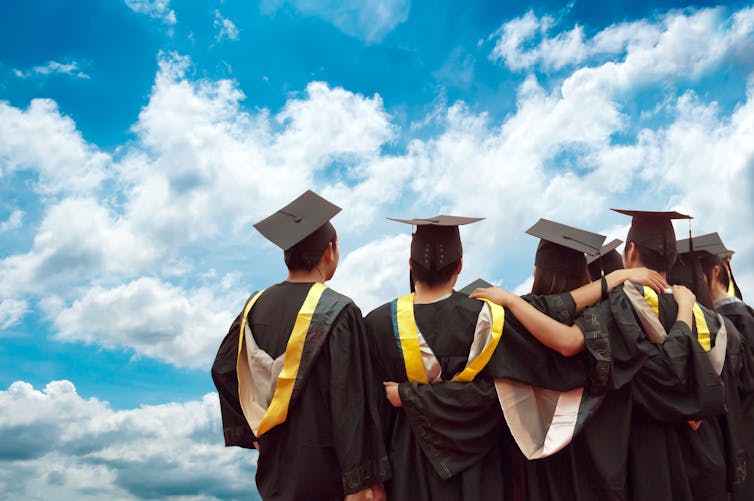 university graduates in academic gowns seen from the
back