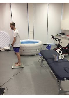Man stands on balance scales next to hot tub.