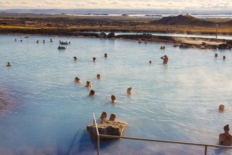 People bathe in a steaming lake.