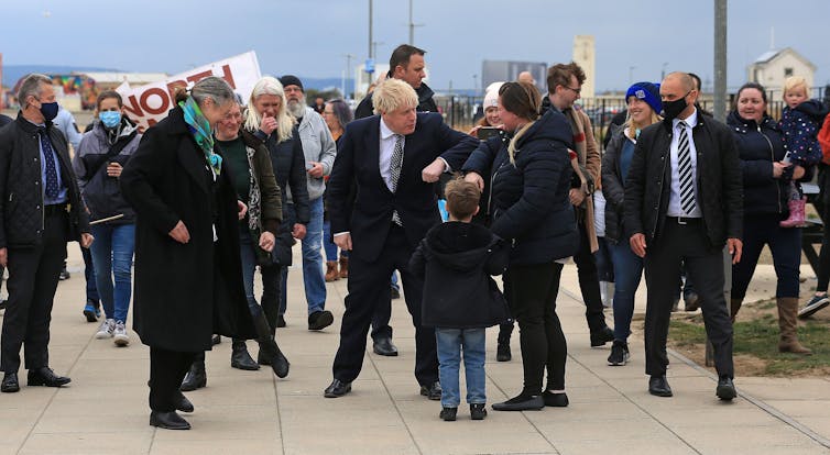 Boris Johnson bumps elbows with a passerby, surrounded by a crowd of people on the sea front in Hartlepool.