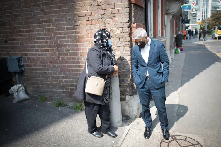 London mayor Sadiq Khan talking to a woman on a London street.