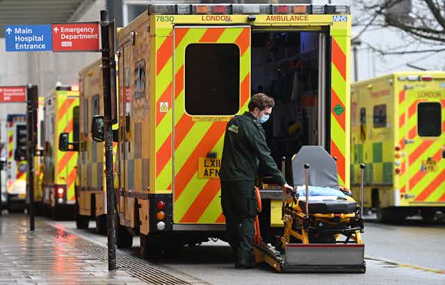 A paramdedic with an empty gurney outside an ambulance. 