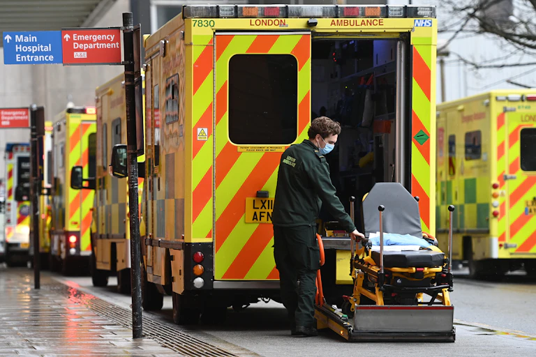 A paramdedic with an empty gurney outside an ambulance.