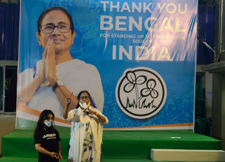 Mamata Banerjee, the chief minister of West Bengal, makes a victory sign in front of an election poster.